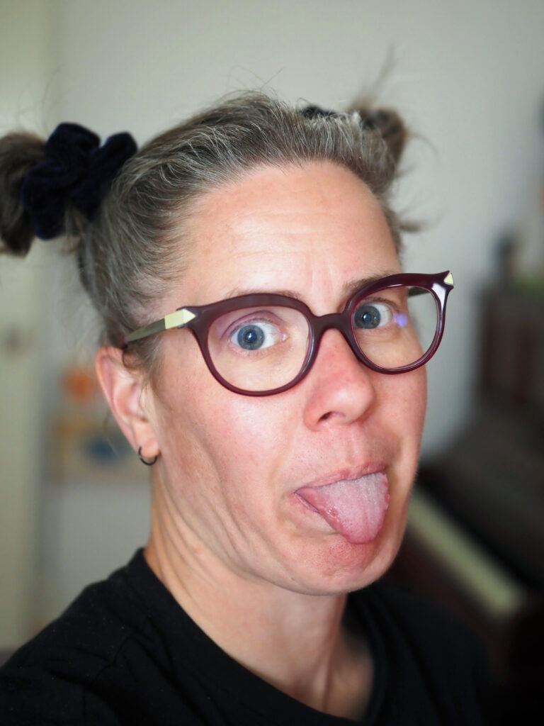 A woman with glasses sticking out her tongue